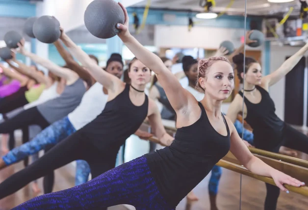 Mujeres haciendo ejercicio Barre juntos en el gimnasio moderno