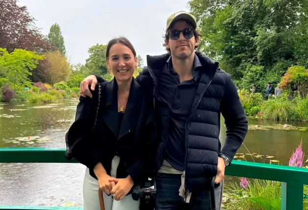 Tamara Falcó e Íñigo Onieva posando abrazados sobre un puente en un parque.