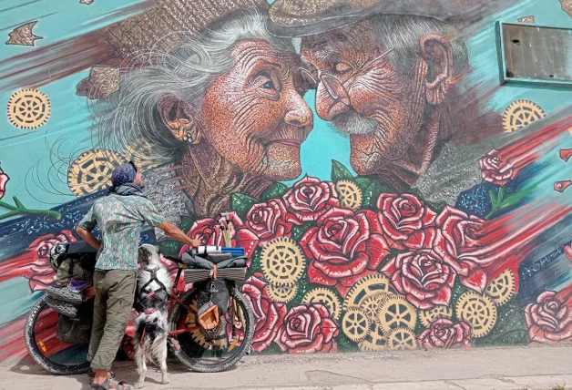 Antonio y Siroco con su bicicleta junto a una impresionante pintura mural.