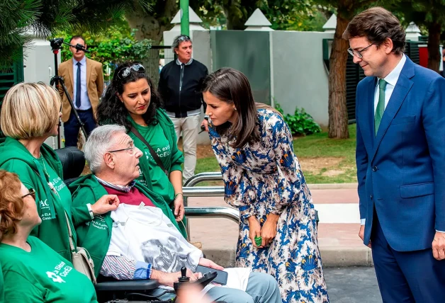 Letizia saludando a un anciano enfermo en silla de ruedas.