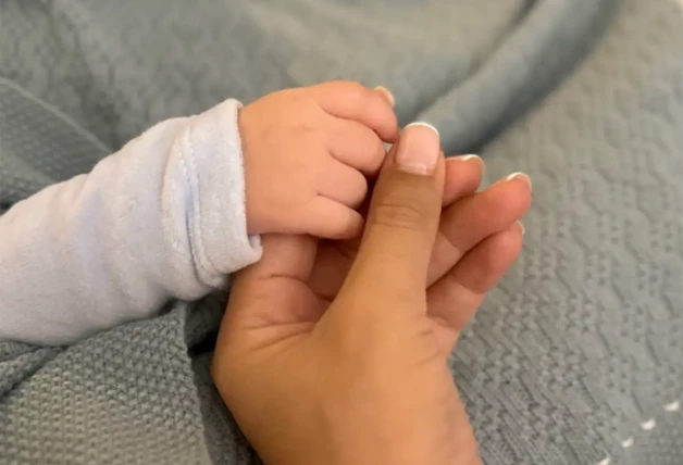 La mano de Gabriela Guillén tomando la manita de su bebé, en una imagen publicada por ella en redes.