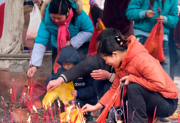 Mujeres chinas encendiendo incienso por sus seres queridos