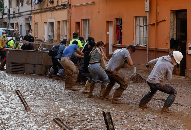 Voluntarios ayudando a los vecinos a desalojar una pesada máquina.