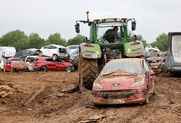 Arriba, un agricultor ayudando a apartar un coche con su tractor.