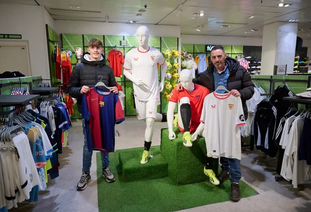 Hombre e hijo posando con sus camisetas de equipos de futbol.