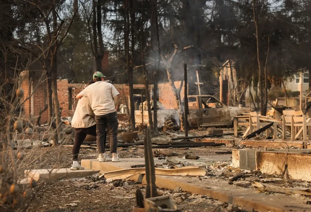 Ciudadanos de Los Ángeles contemplando el lugar donde solía estar su casa, ahora quemada por el fuego.