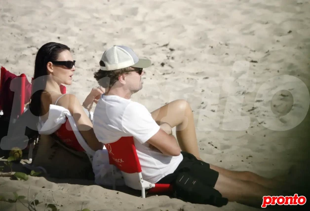 Leonardo DiCaprio con su novia sentados en la playa.