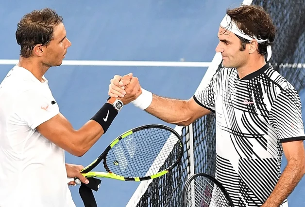 Rafa Nadal y Roger Federer saludándose en una pista de tenis.