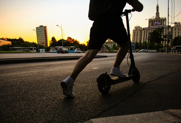 Joven conduciendo un patinete eléctrico por una ciudad.