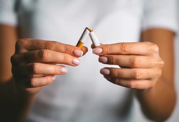 Mujer que rompe un cigarrillo en dos