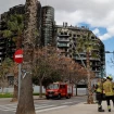 Bomberos delante de un edificio quemado.