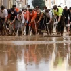 Voluntarios "barriendo" el exceso de agua fuera de las calles de Masanasa.