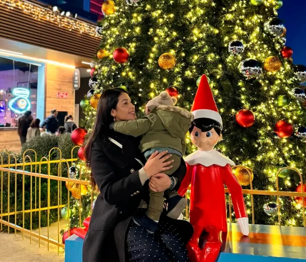 Gabriela Guillén con su bebé en brazos delante de un árbol de Navidad.