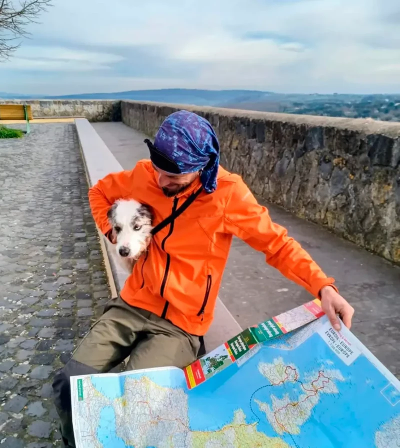 Antonio acaricia a su perro Siroco mientras mira un mapa mundi.