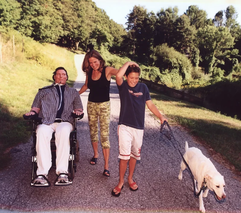 Christopher Reeve paseando en silla de ruedas junto a su mujer y a su hijo.