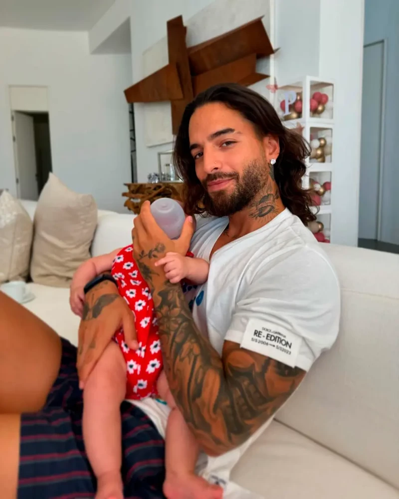 Maluma da el biberón a su hija sentado en el sofá de su casa