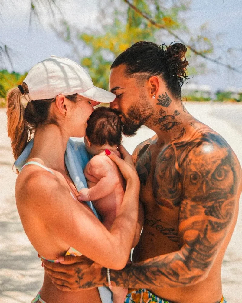 Maluma y su mujer sujetan y besan a su hija junto al mar