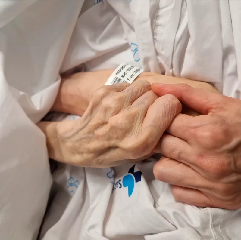 La mano de Ania Iglesias tomando la mano de su madre enferma en el hospital