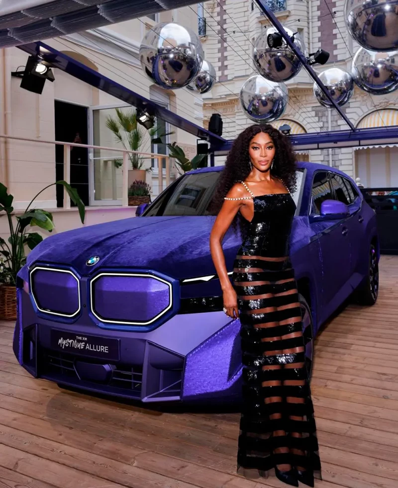 Naomi Campbell posa junto a un coche de lujo.