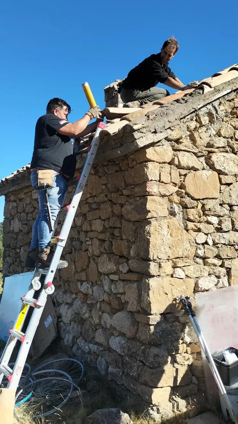 Montañeros reparando un refugio de montaña.