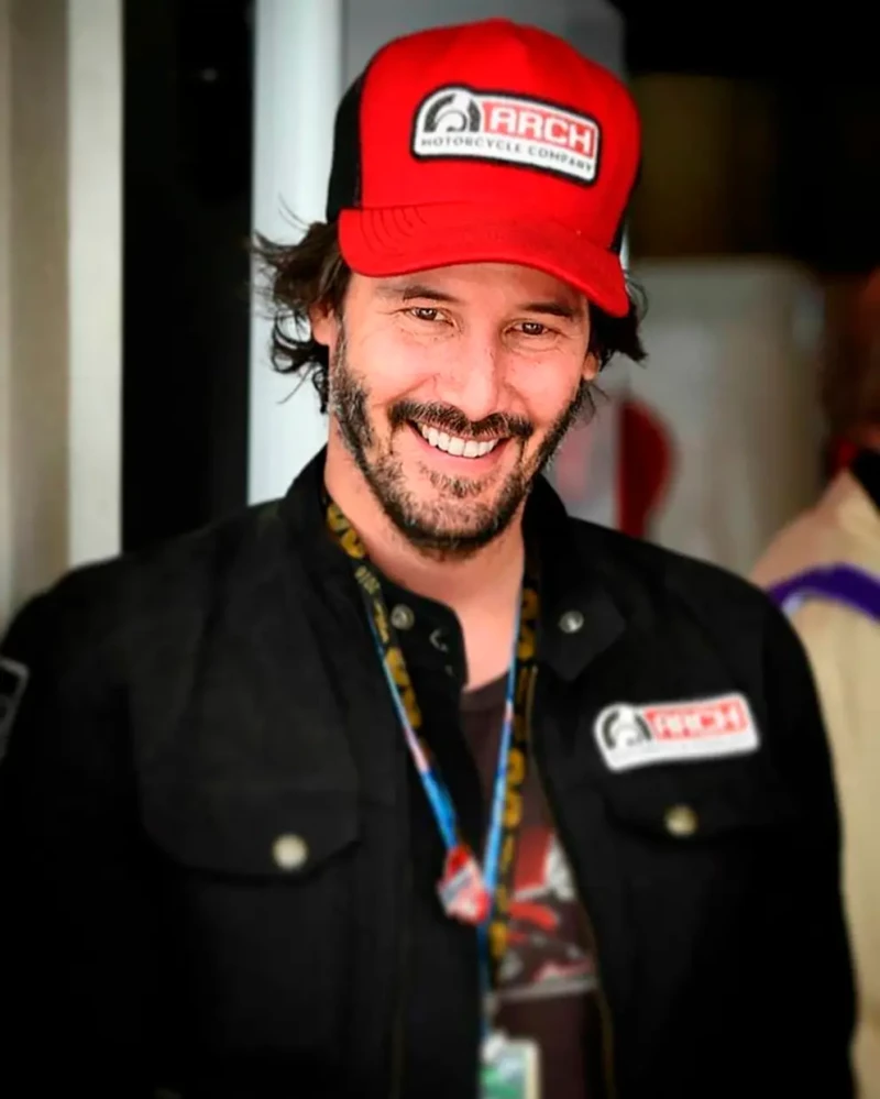 El actor Keanu Reeves vestido con la ropa de la escudería de coches de carreras.