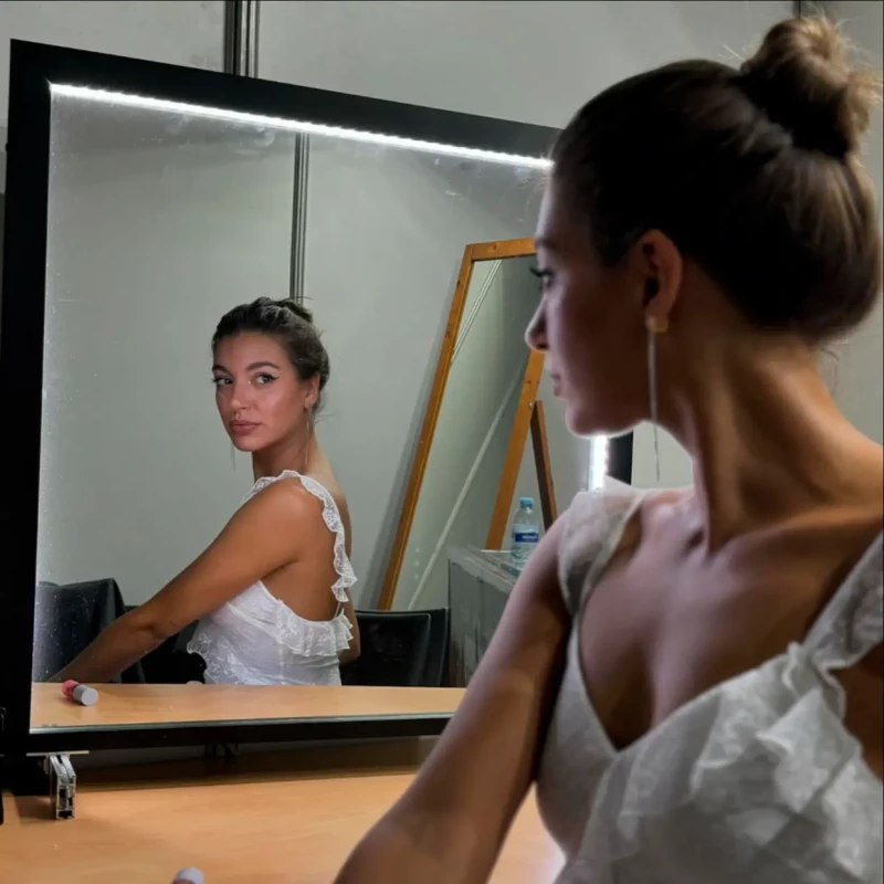 Ana Guerra vestida de blanco mirándose al espejo.