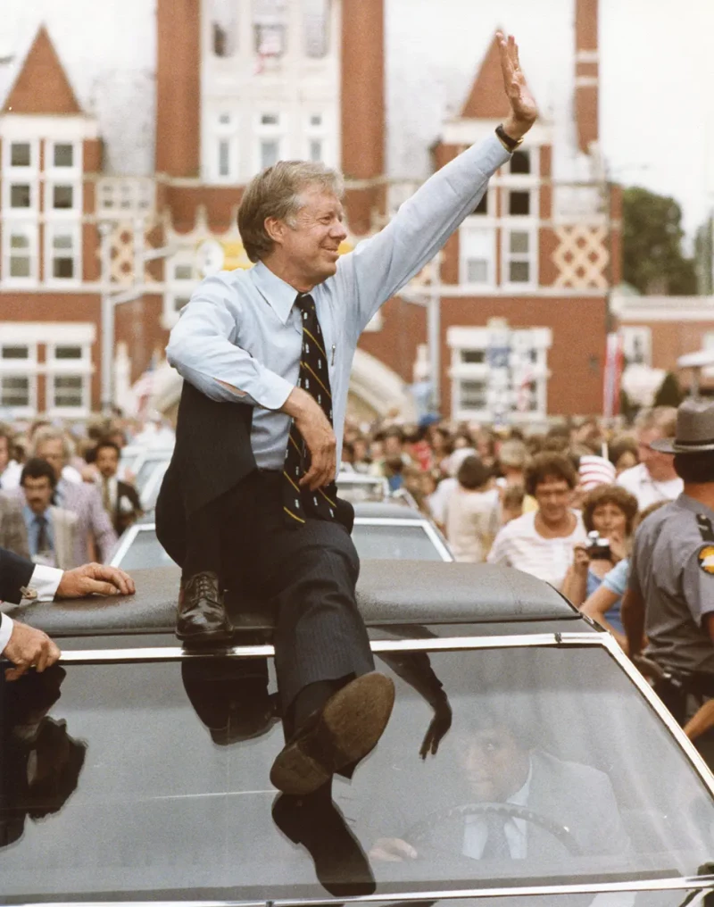 El expresidente Jimmy Carter subido al techo de un coche, saludando a sus votantes.