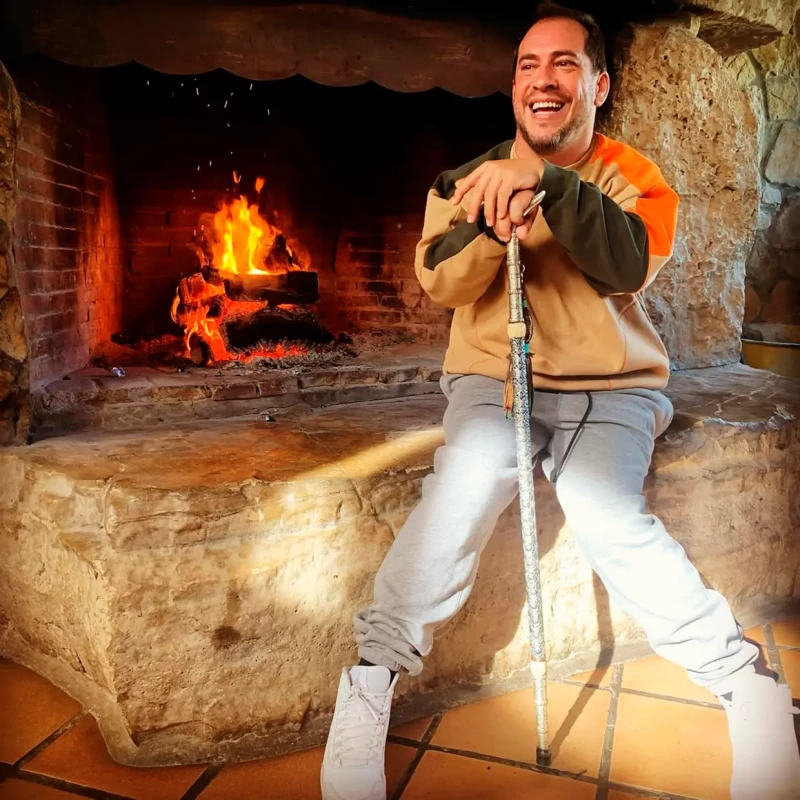 El Langui junto a una chimenea, posa sonriente con su muleta