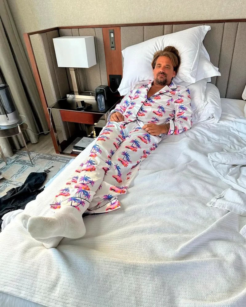 Sean Stewart en pijama tumbado en una cama de sábanas blancas