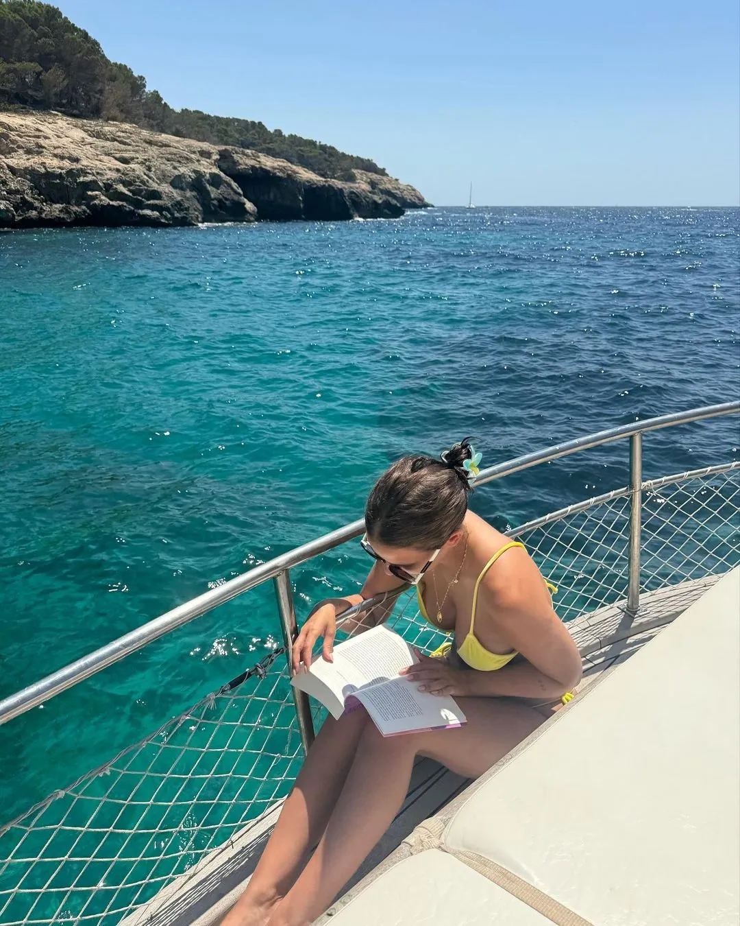 Laura está usando sus vacaciones para leer cerca del mar.