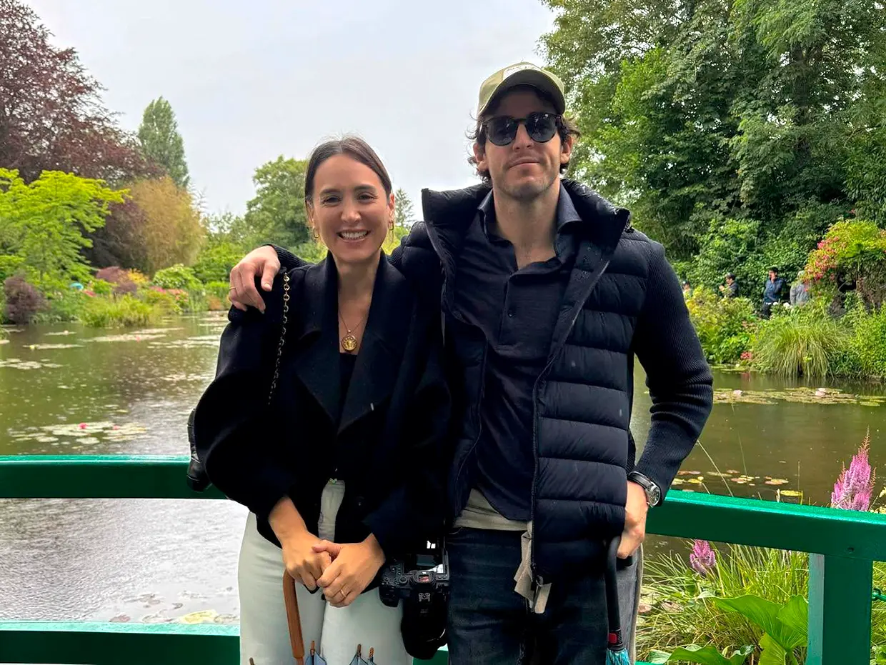 Tamara Falcó e Íñigo Onieva posando abrazados sobre un puente en un parque.