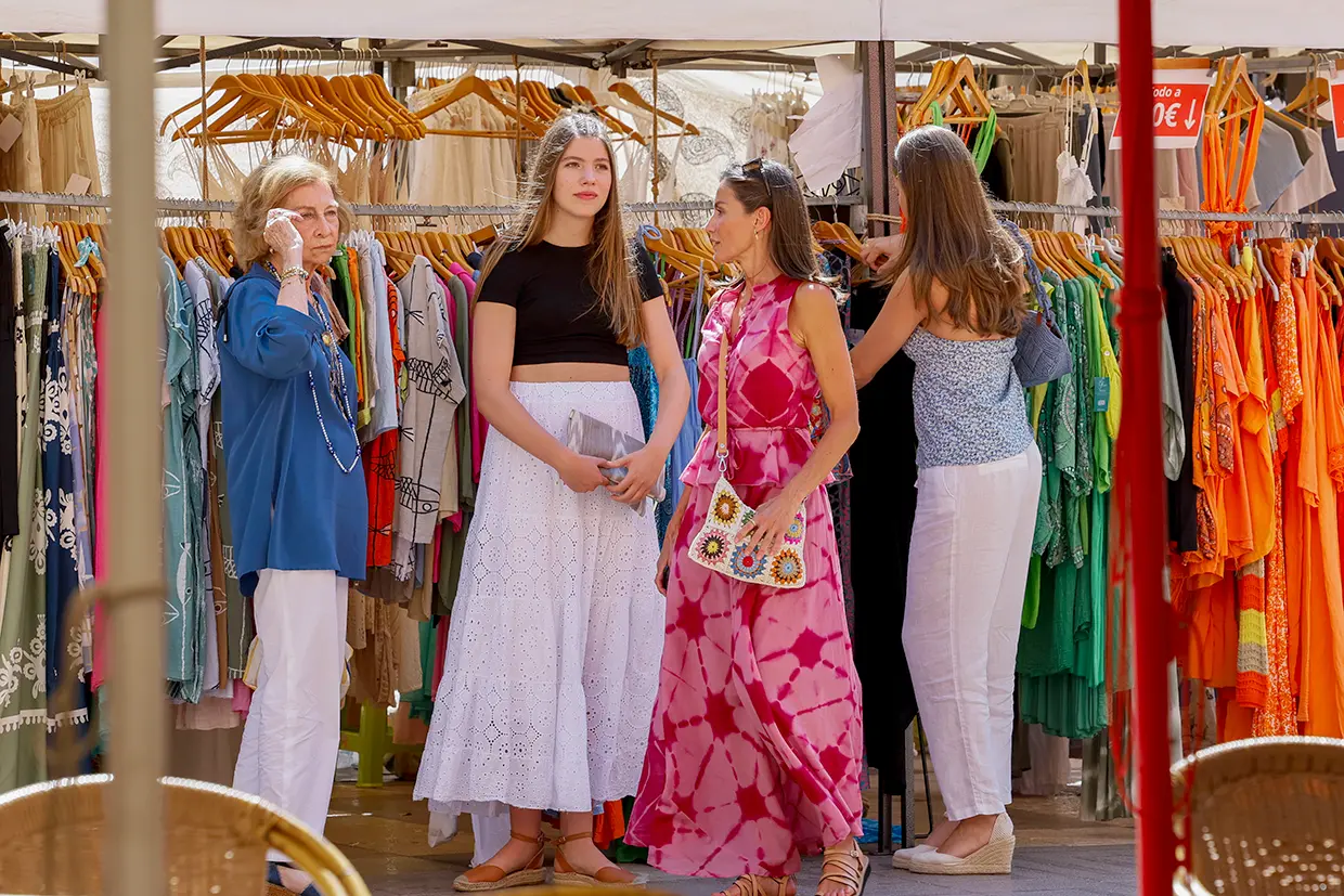 Letizia con sus hijas y la reina sofía mirando vestidos en un mercadillo de Mallorca.