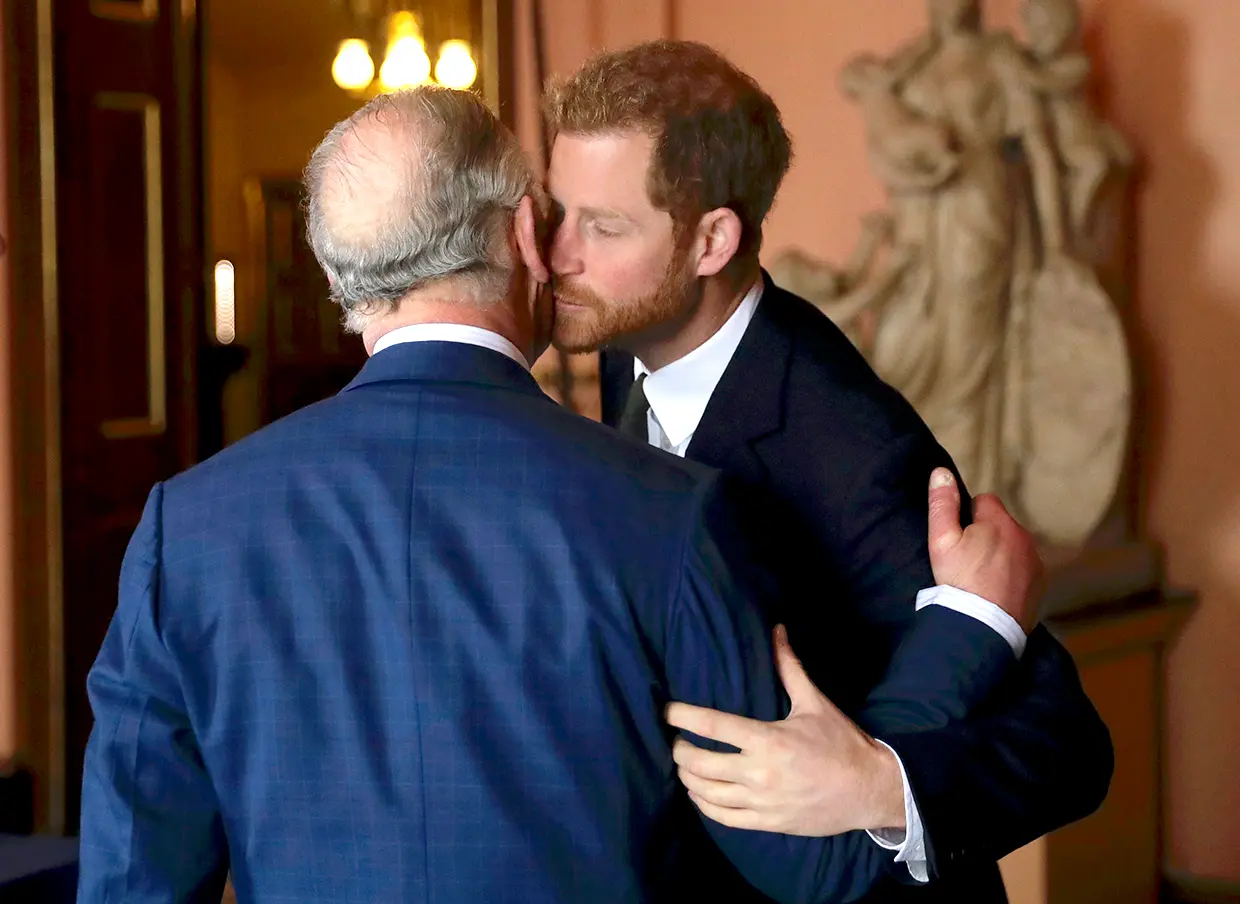 El rey Carlos de Inglaterra y su hijo Harry dándose un beso