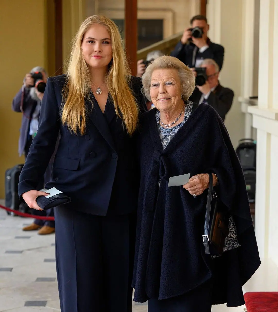 Con traje oscuro junto a su abuela.