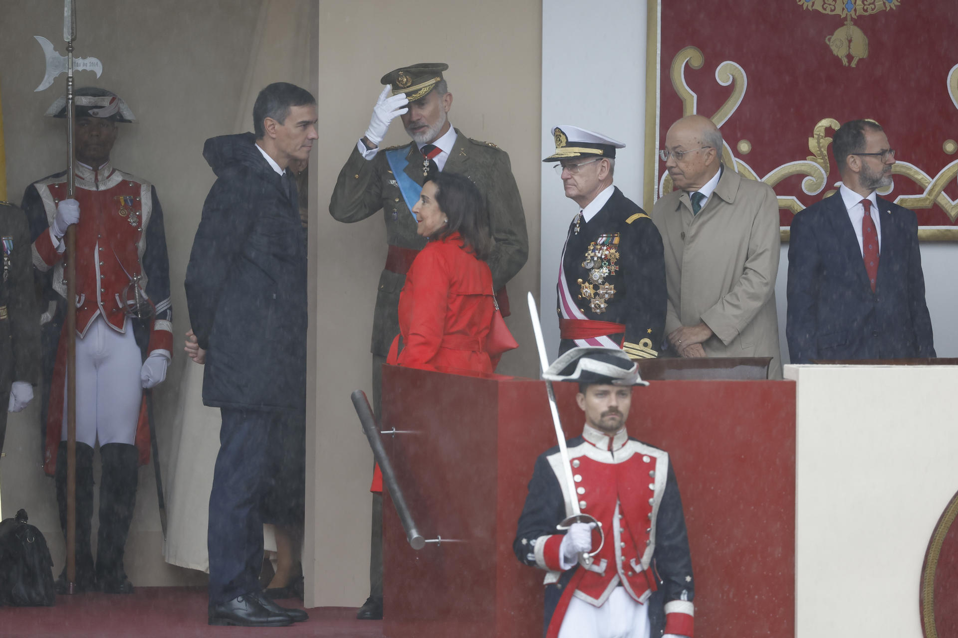 El rey Felipe VI conversa con el presidente del Gobierno y con la ministra de Defensa, en el tradicional desfile del Día de la Fiesta Nacional.