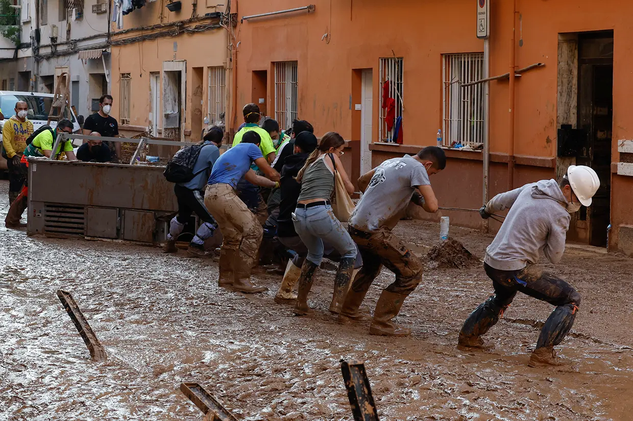 Voluntarios ayudando a los vecinos a desalojar una pesada máquina.